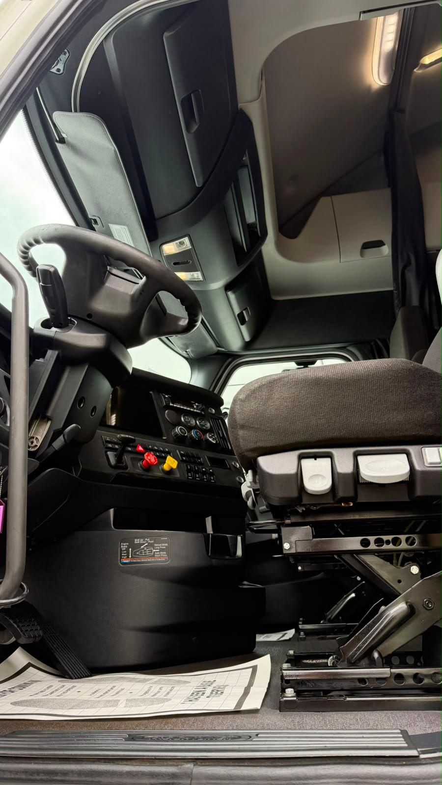 Clean semi cab looking back into the sleeper, with driver seat and dashboard