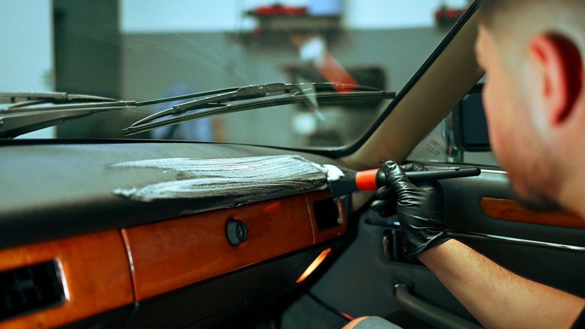 Cleaner detailing a vehicle dashboard with a brush